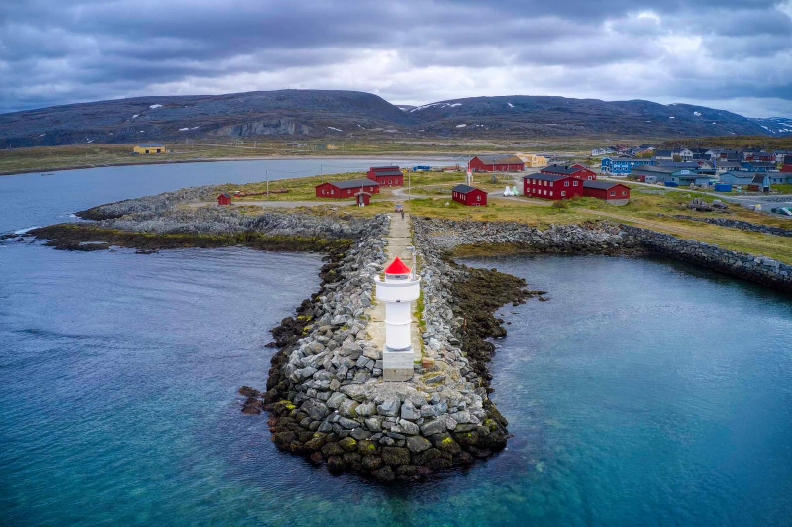 Flyfoto av moloen i Berlevåg med rødt fyr.